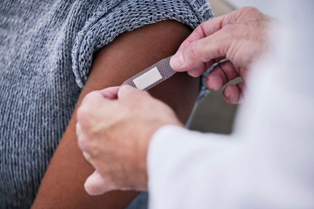 Pharmacienne collant un pansement après une vaccination d'un patient